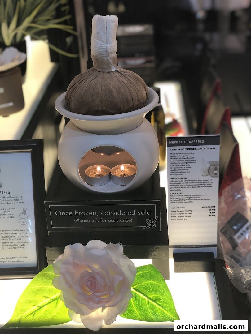 A display featuring a herbal compress with a warmer, candles, and a rose.