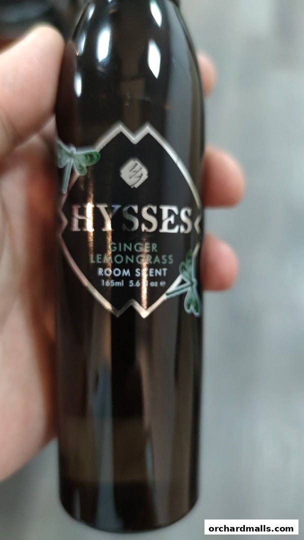 A hand holds a dark bottle of HYSSES Ginger Lemongrass Room Scent.