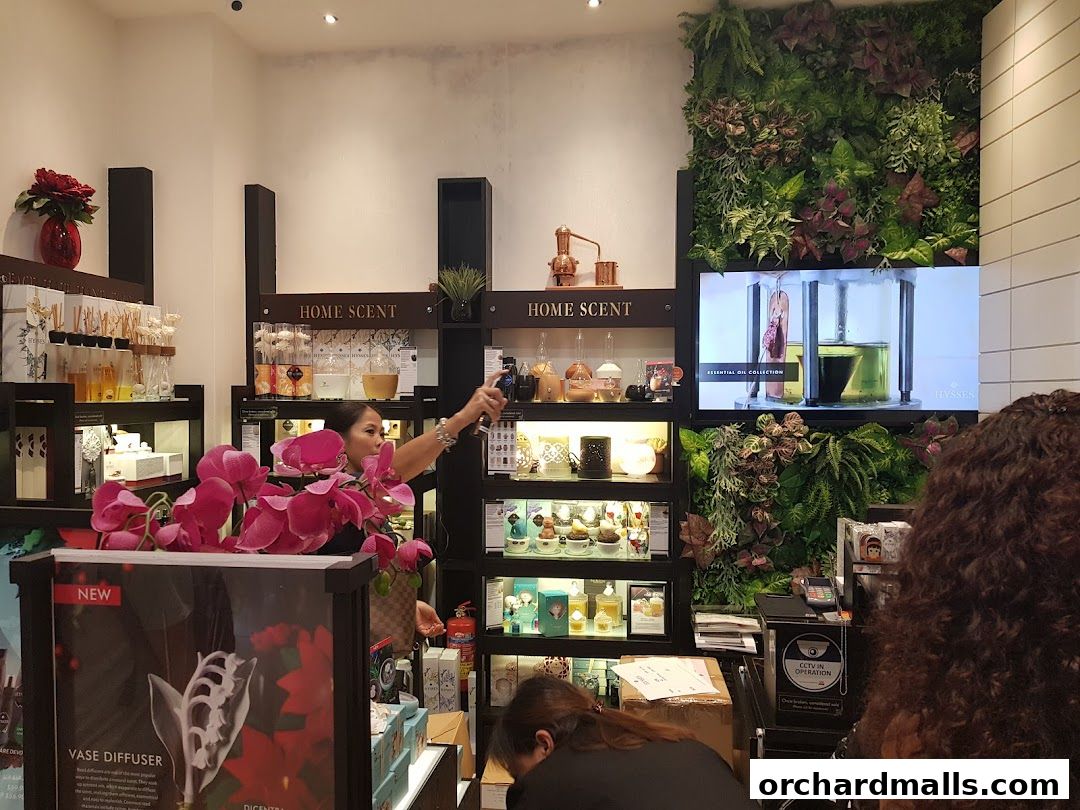 A woman sprays a product in a shop filled with essential oils and home scent products.