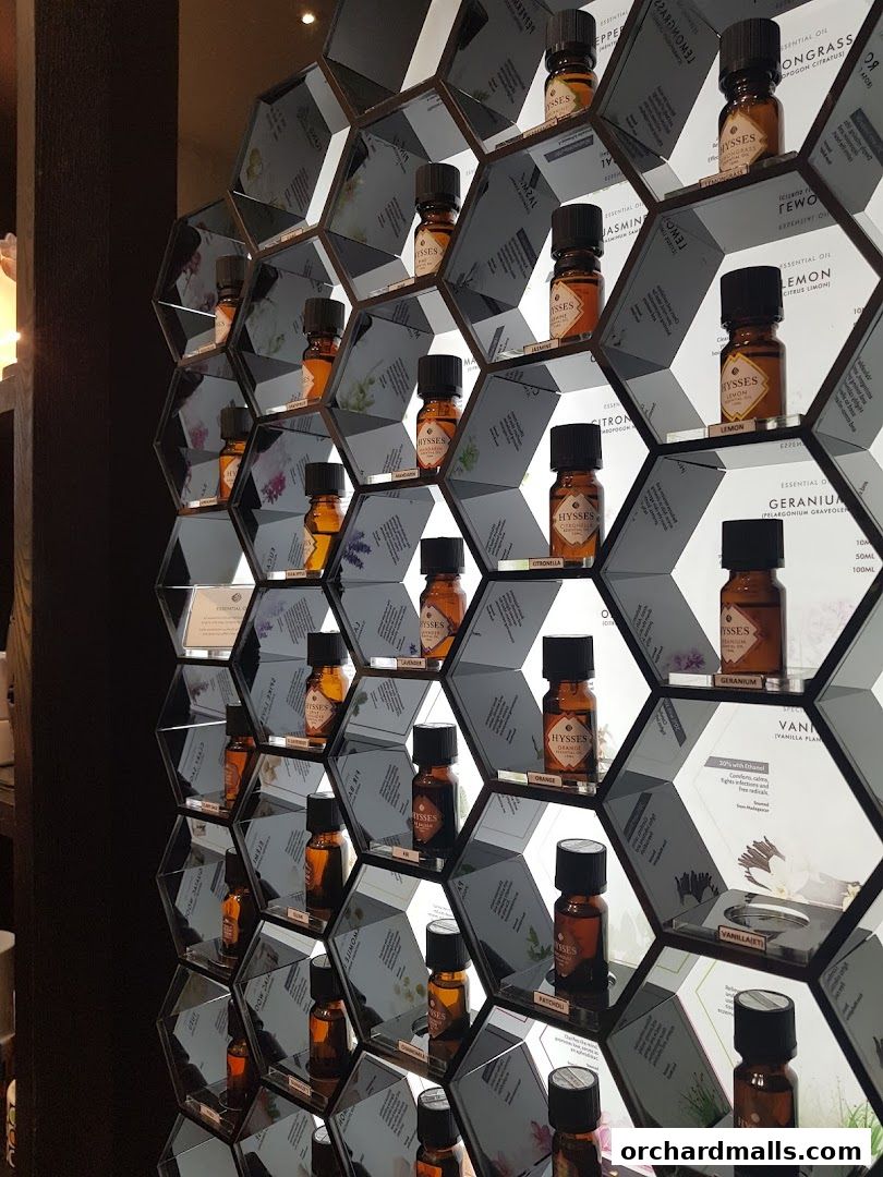 A wall display featuring hexagonal shelves filled with small bottles of essential oils.