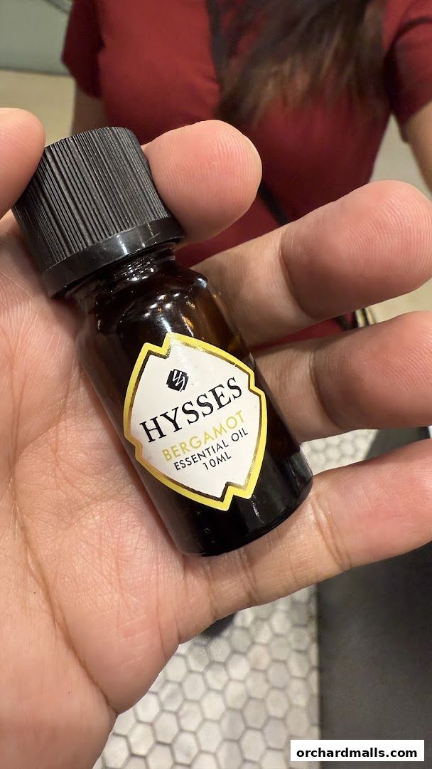 A hand holds a small bottle of HYSSES Bergamot Essential Oil.