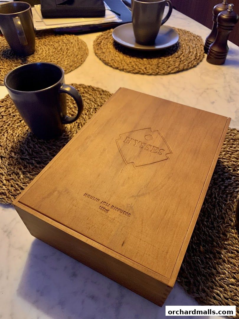 A wooden box with the HYSSES logo and text on a table with mugs.