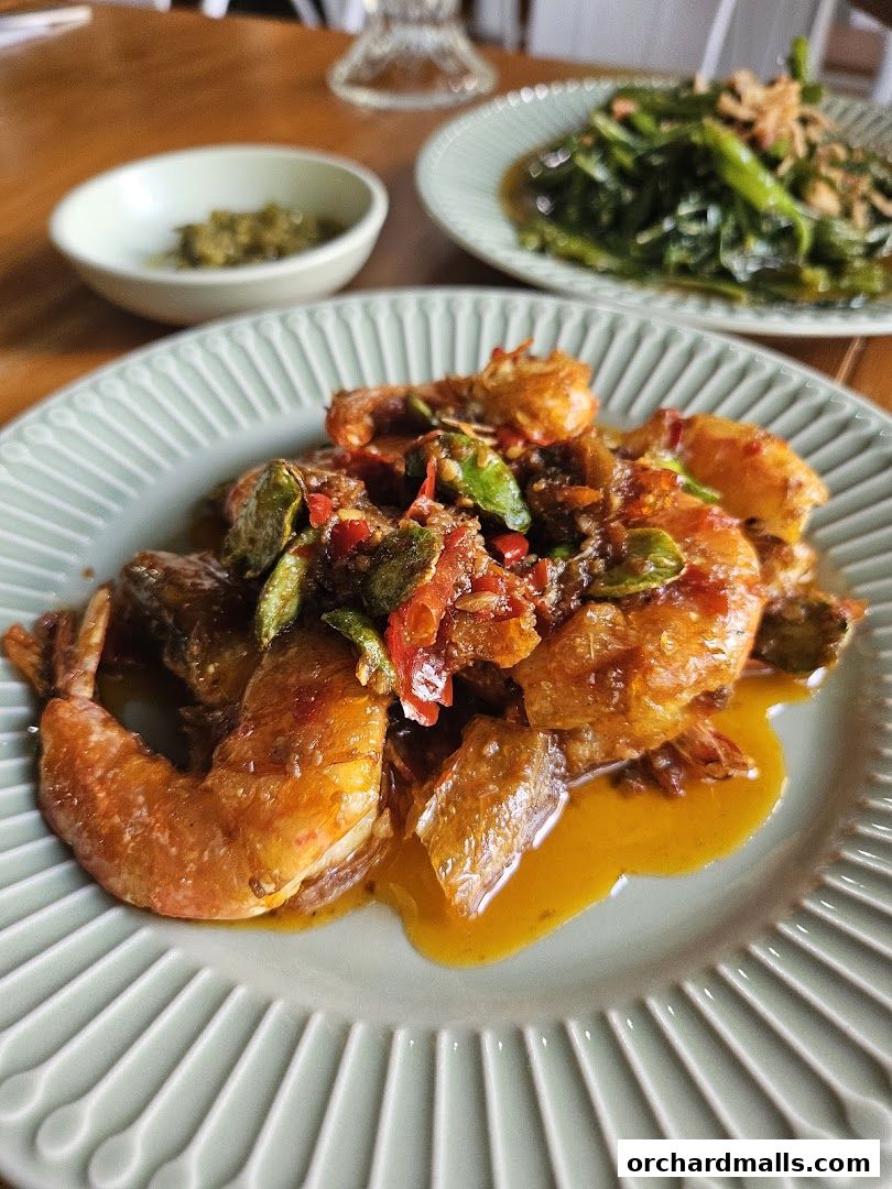 A close-up of a plate of spicy prawns with a side dish of vegetables.