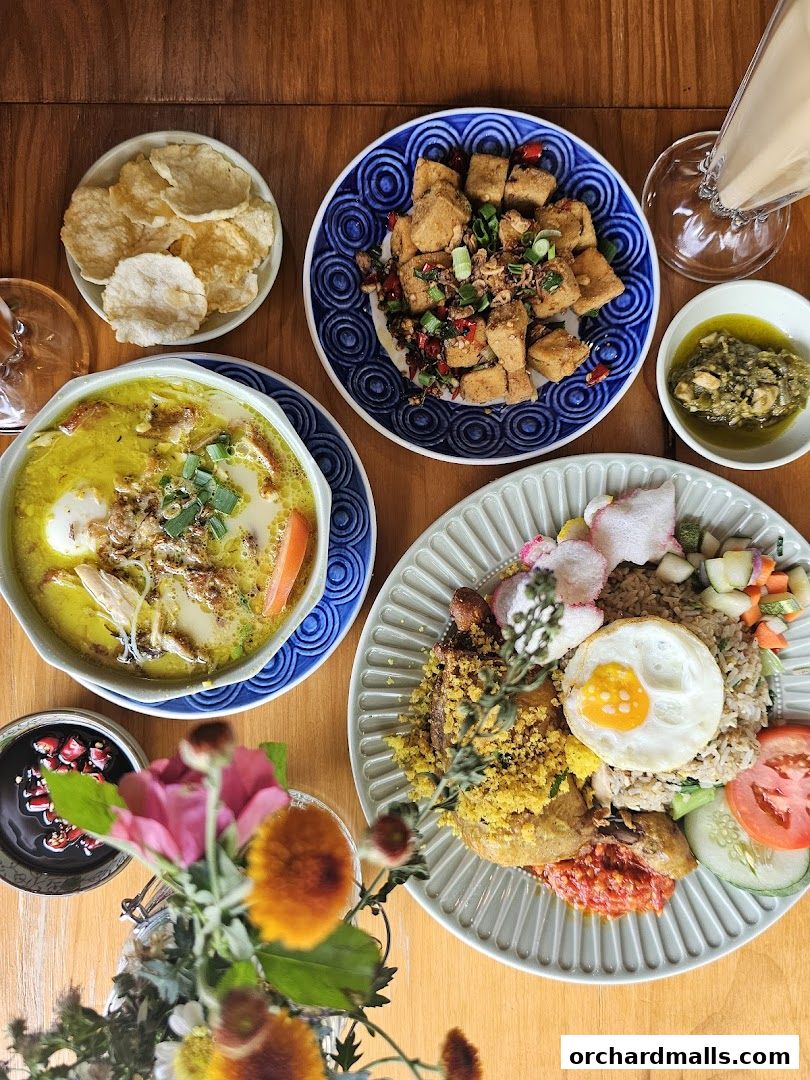 A top-down view of a table laden with delicious Indonesian dishes and a floral arrangement.