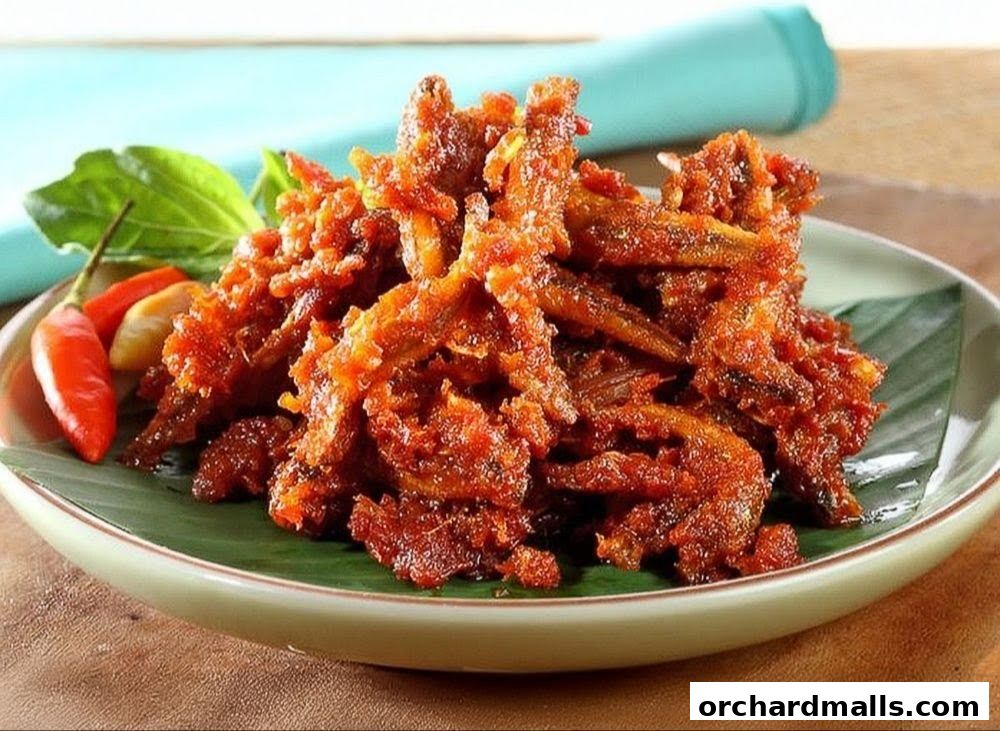 A close-up of a plate of crispy fried anchovies with chili and basil leaves.