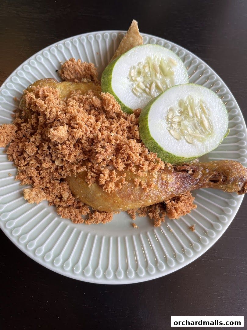 A plate of crispy fried chicken with cucumber slices and crumbs.