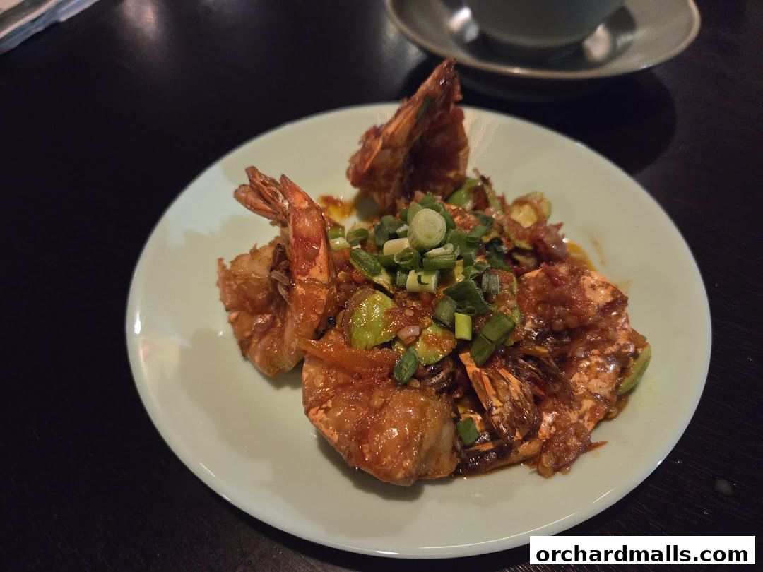 A plate of delicious stir-fried prawns with green onions and a savory sauce.