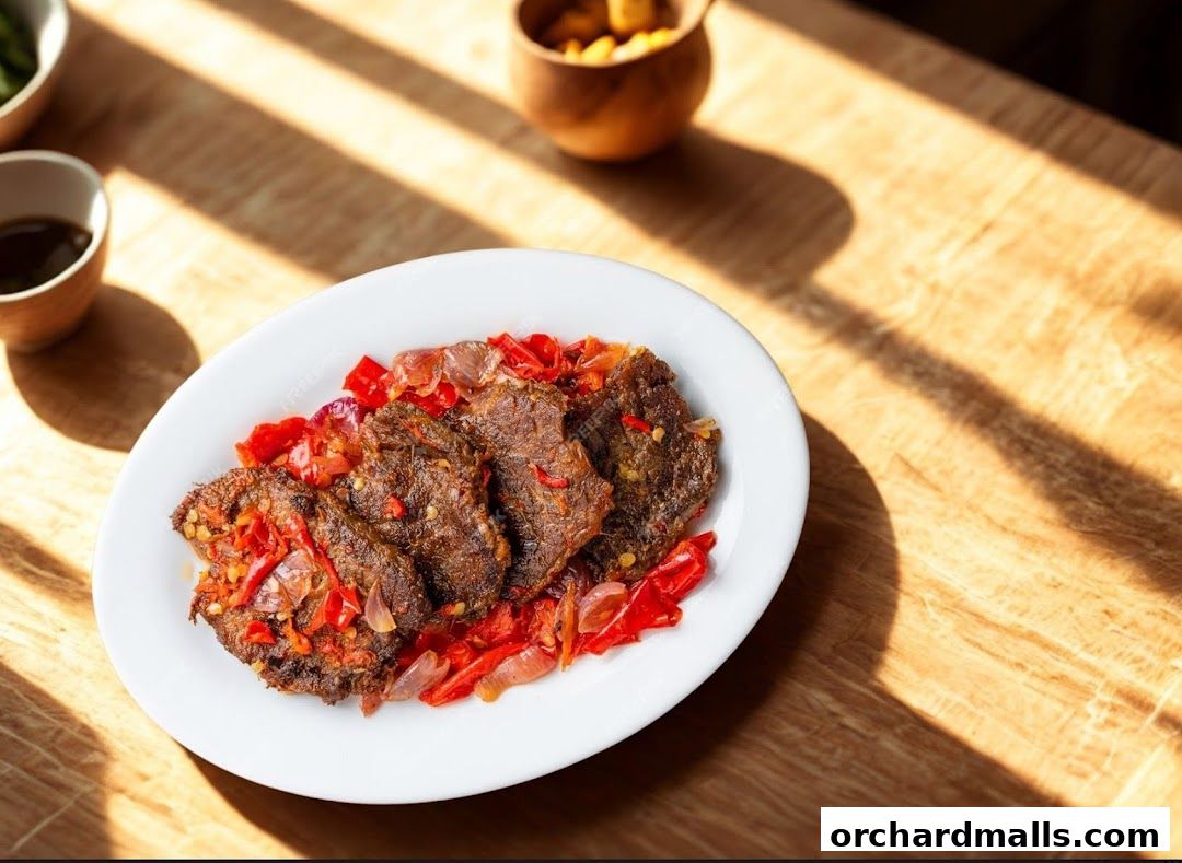 A plate of tender beef with chili and onions served on a wooden table.