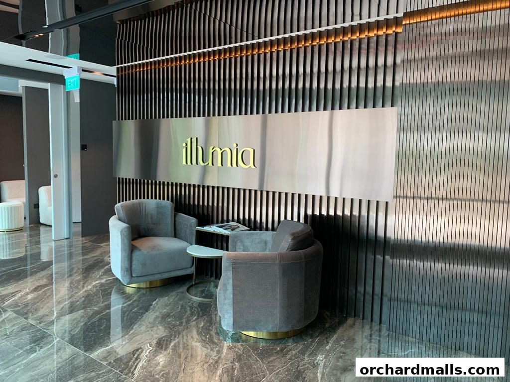 Elegant waiting area with plush chairs and the 'illumia' logo on a metallic wall.