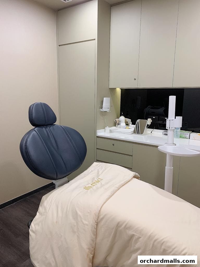 Interior of an aesthetic clinic room with a treatment bed and chair.