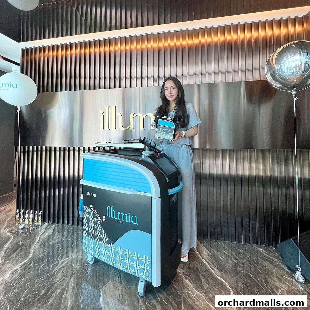 A woman stands next to a medical aesthetic machine at Illumia Medical Orchard.