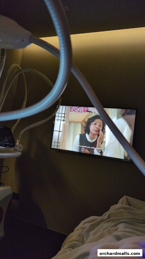 A screen displays a woman applying makeup, with medical equipment in the foreground.
