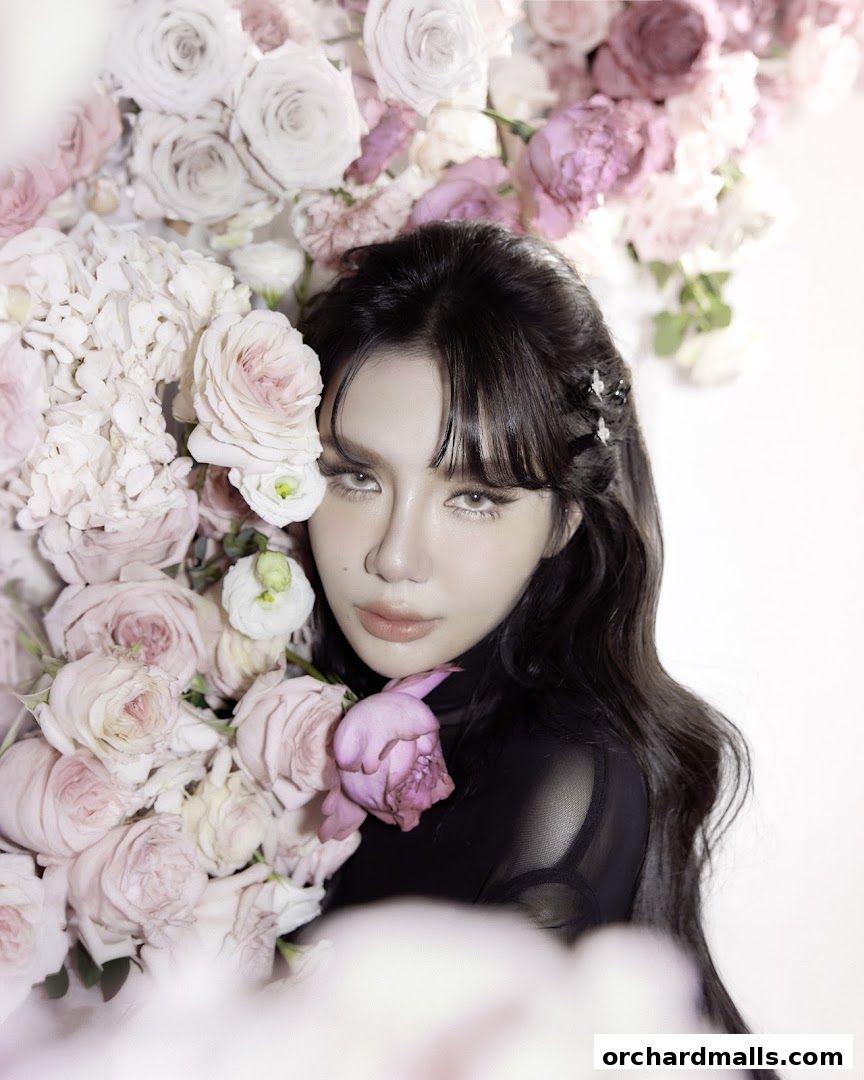 A woman with dark hair poses with a large arrangement of pink and white roses.
