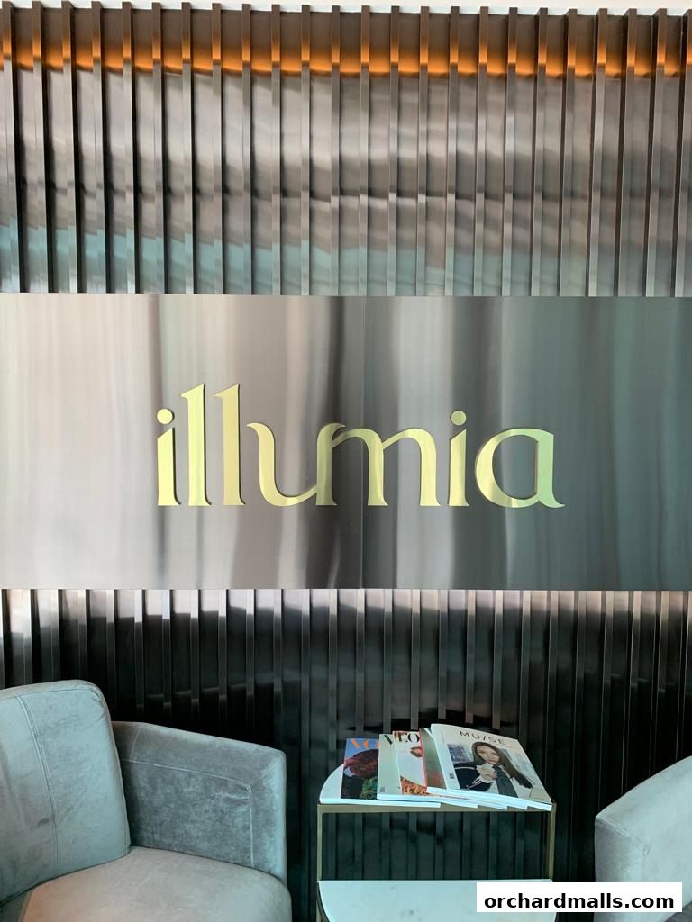 Illumia Therapeutics logo on a metallic wall with seating and magazines.