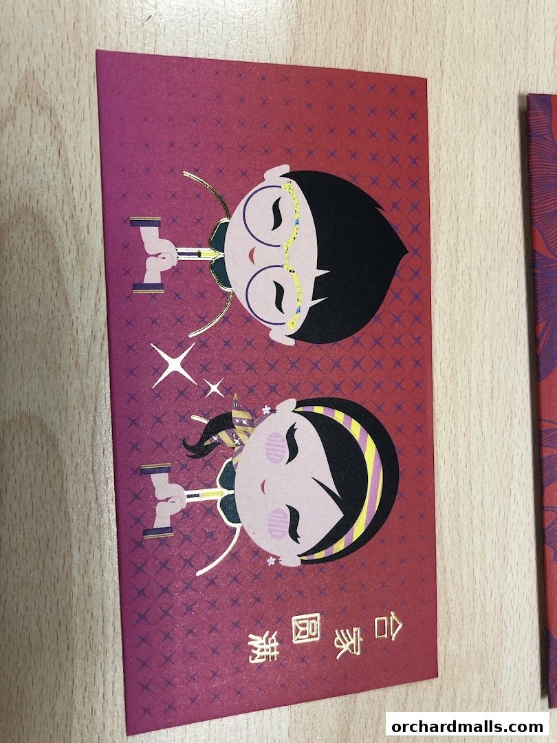 Red envelopes with cartoon characters and gold Chinese characters on a wooden surface.
