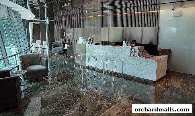 The reception area of illumiaFace by Kim Lim, featuring plush seating and a marble counter.