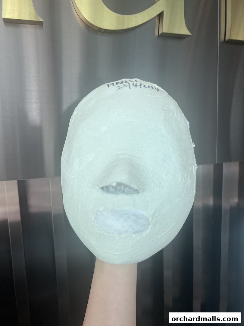 A plaster cast of a face with eyes and mouth openings, held by a hand.