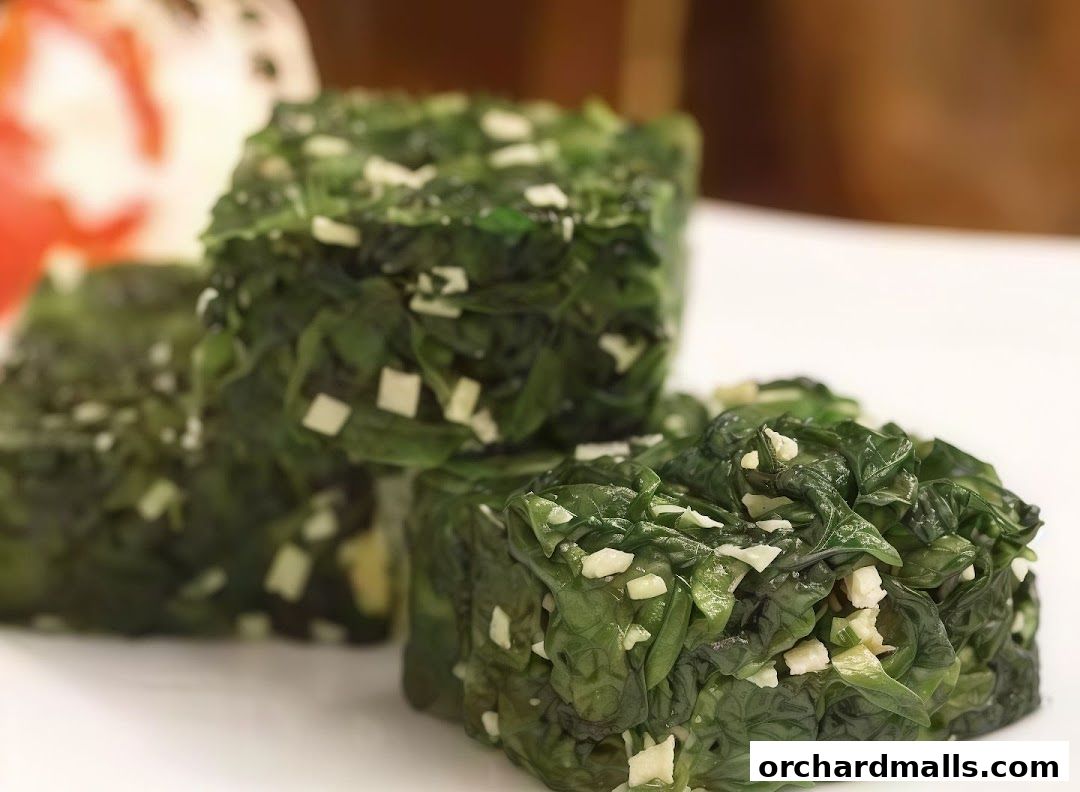 A close-up shot of a dish of cooked spinach with chopped garlic.