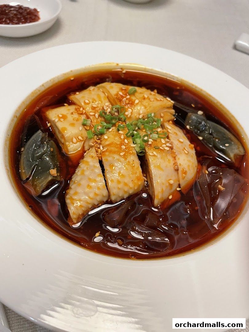 A close-up of a delicious Shanghai-style chicken dish with century eggs and noodles.