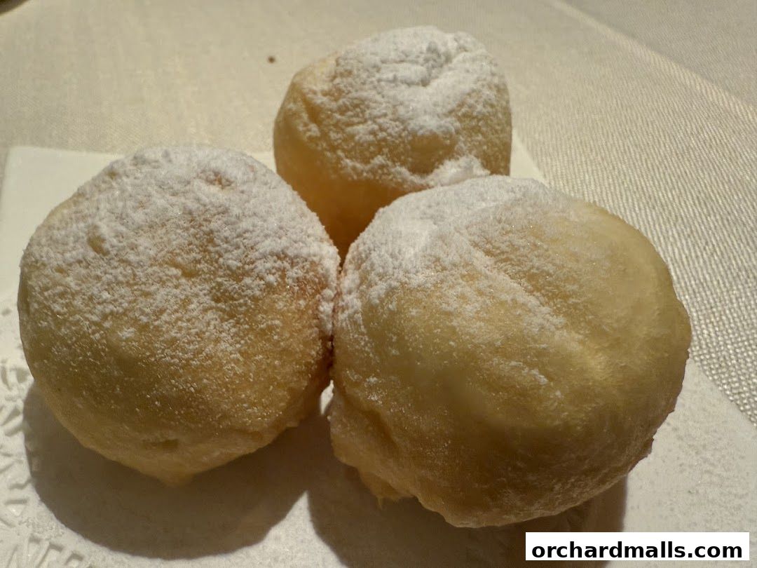 Three golden-brown fried dough balls dusted with powdered sugar.