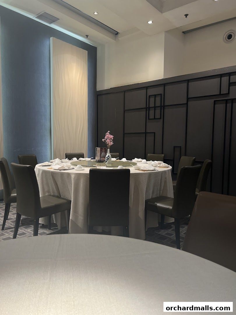 A round dining table set for a meal with chairs around it in a restaurant.