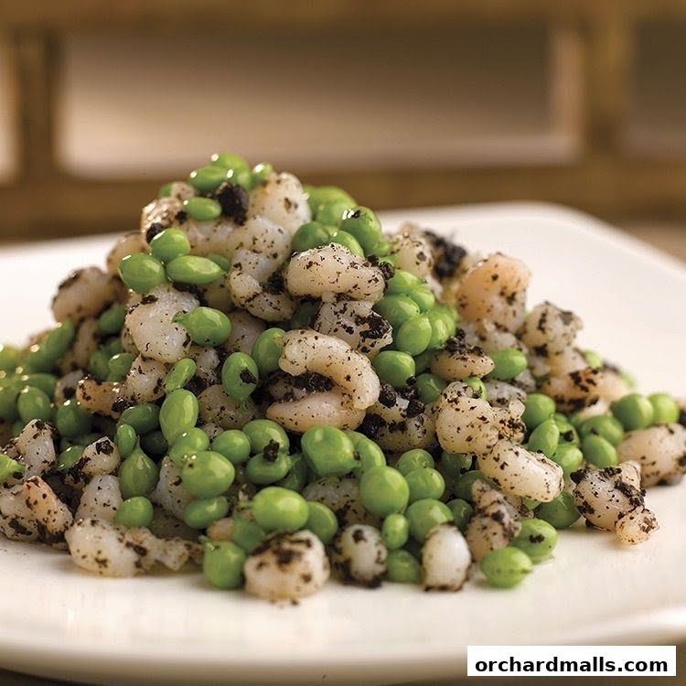A close-up shot of a dish featuring shrimp and edamame beans seasoned with black pepper.