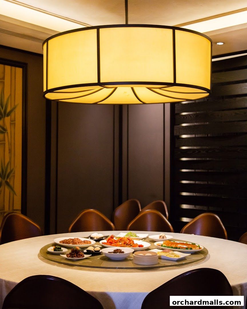 A round dining table set with various Shanghai cuisine dishes under a large pendant light.