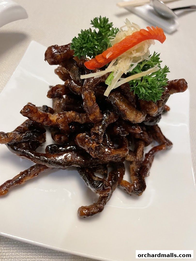 A plate of crispy, glazed Shanghai-style beef strips garnished with parsley and chili.