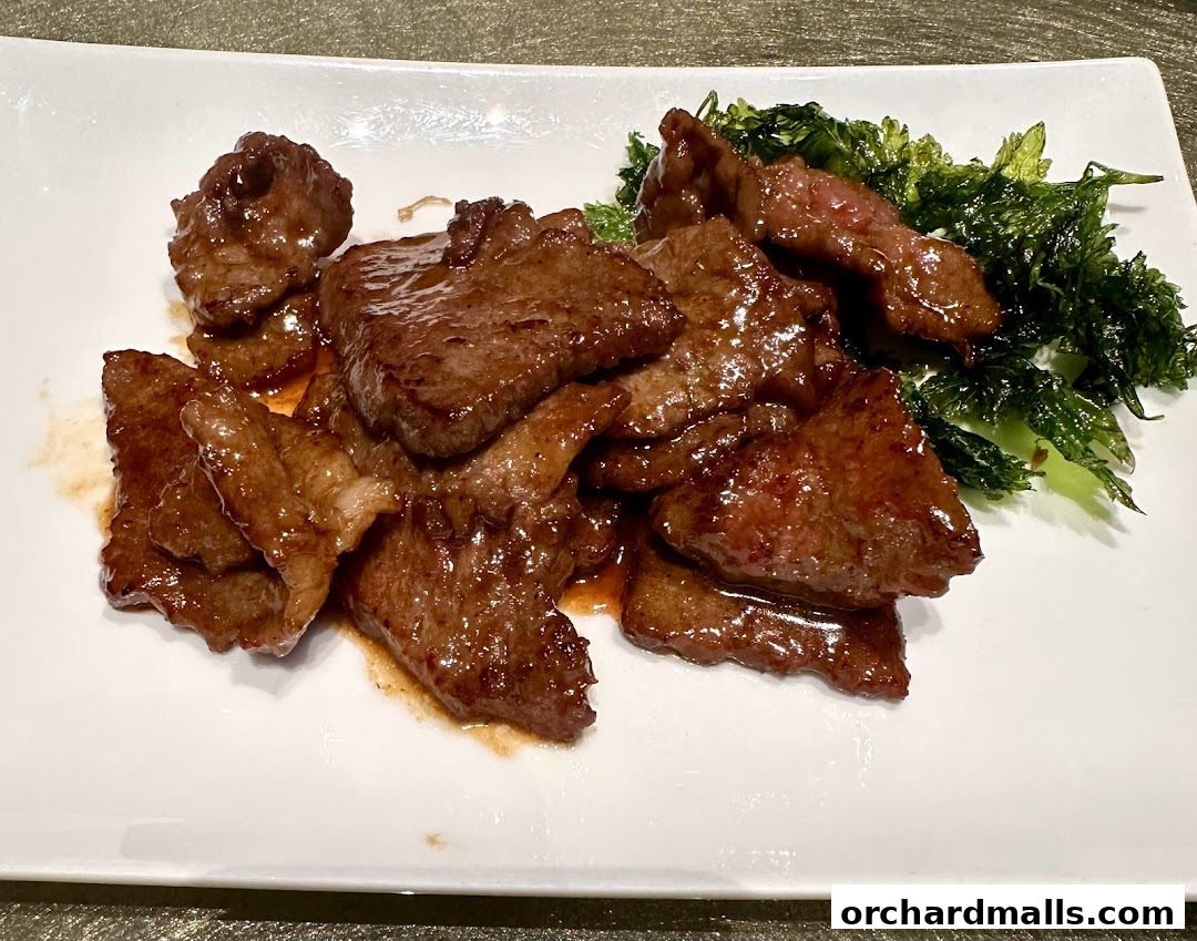 A plate of tender, glazed beef slices served with crispy green vegetables.