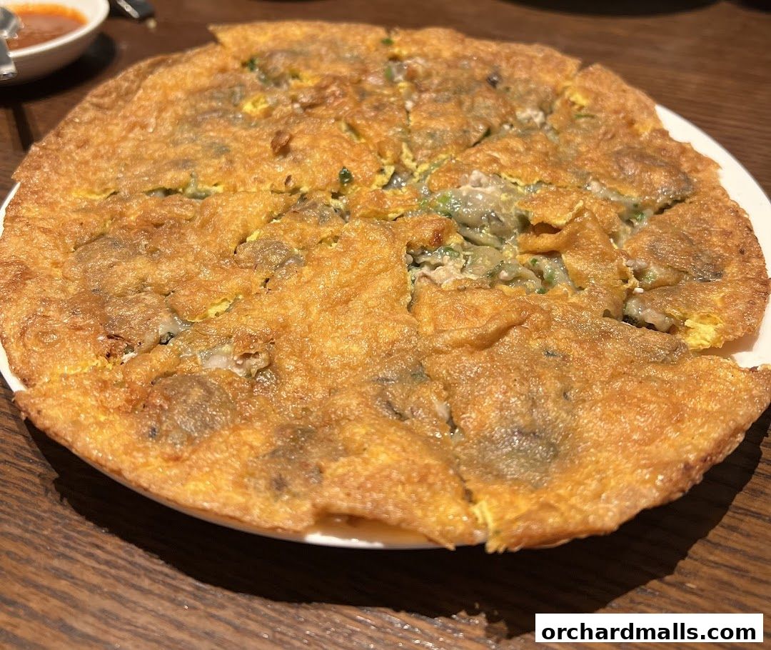 A close-up shot of a golden-brown oyster omelet served on a white plate.