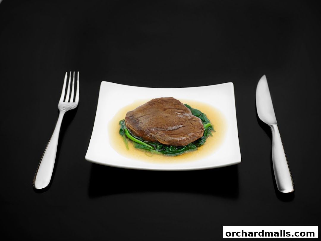 A plate of braised beef with spinach, served with a fork and knife.