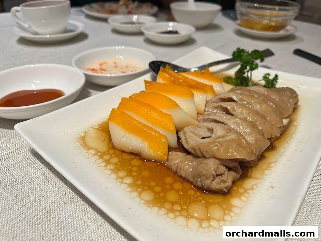 A plate of sliced chicken and jelly-like dessert with dipping sauces on a table.