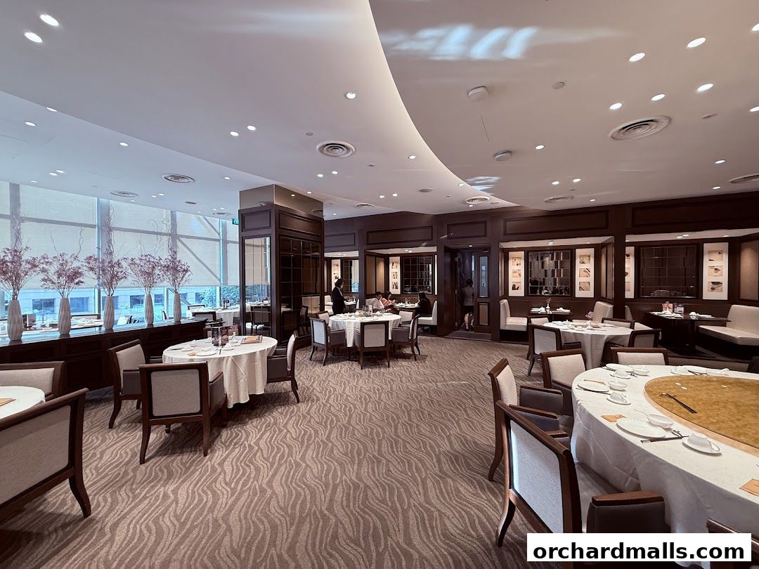 Elegant dining room with round tables set for a meal, featuring plush seating and decorative elements.
