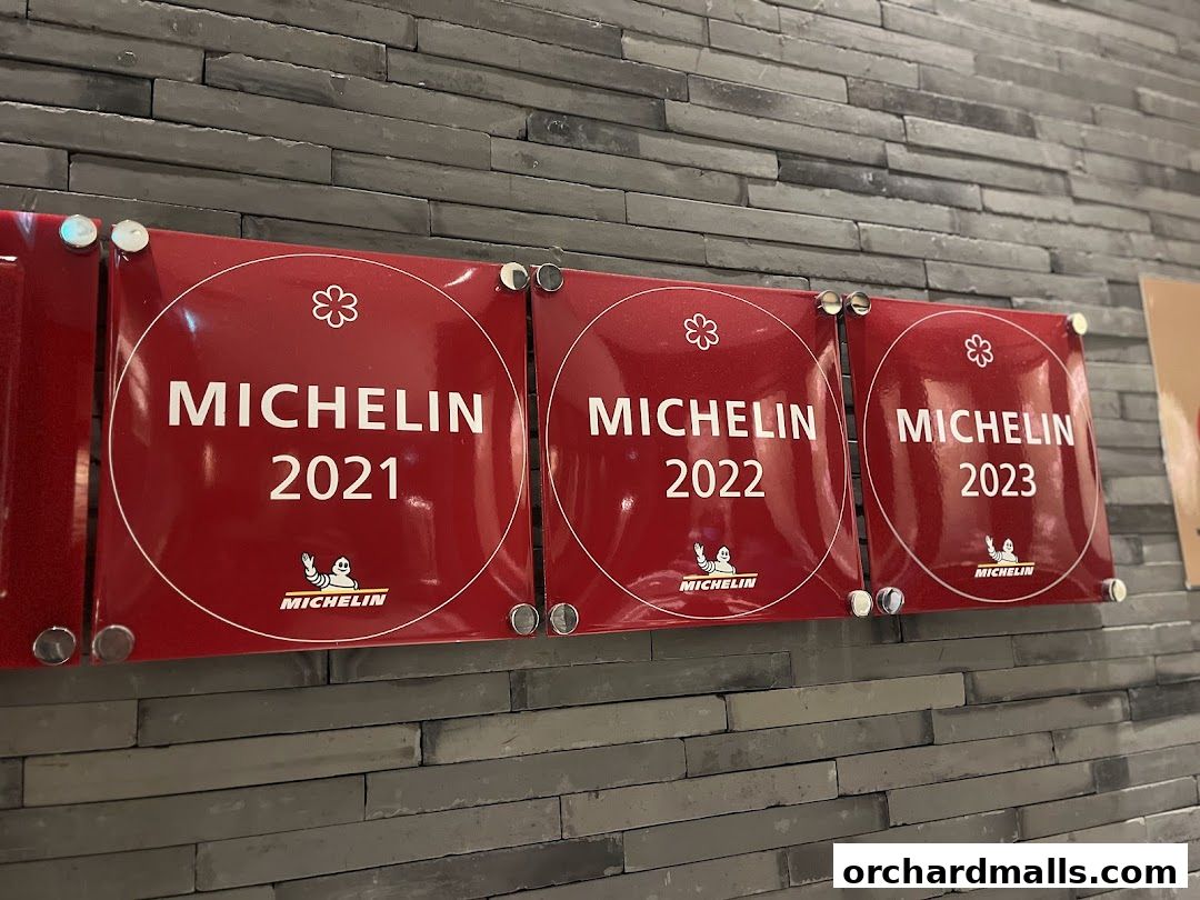 Three red Michelin Guide awards for 2021, 2022, and 2023 displayed on a stone wall.