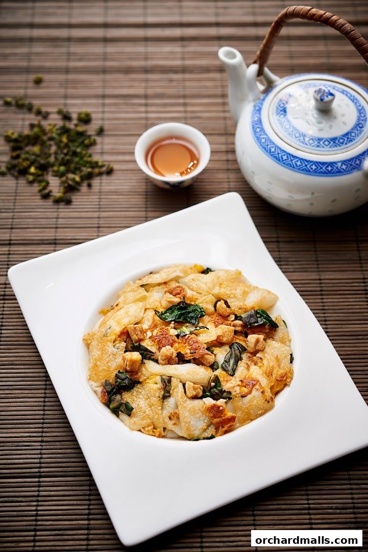 A plate of Teochew cuisine with a teapot and tea cup on a bamboo mat.