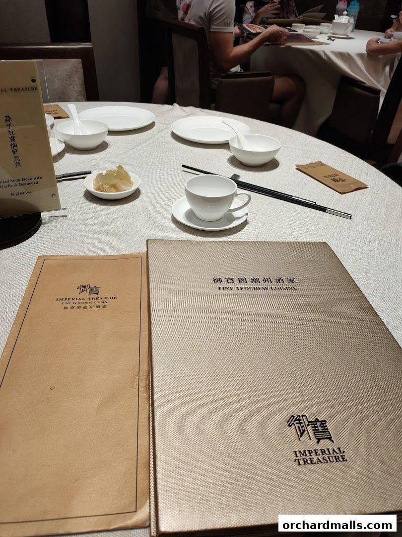 A table setting at Imperial Treasure Fine Teochew Cuisine with menus and place settings.