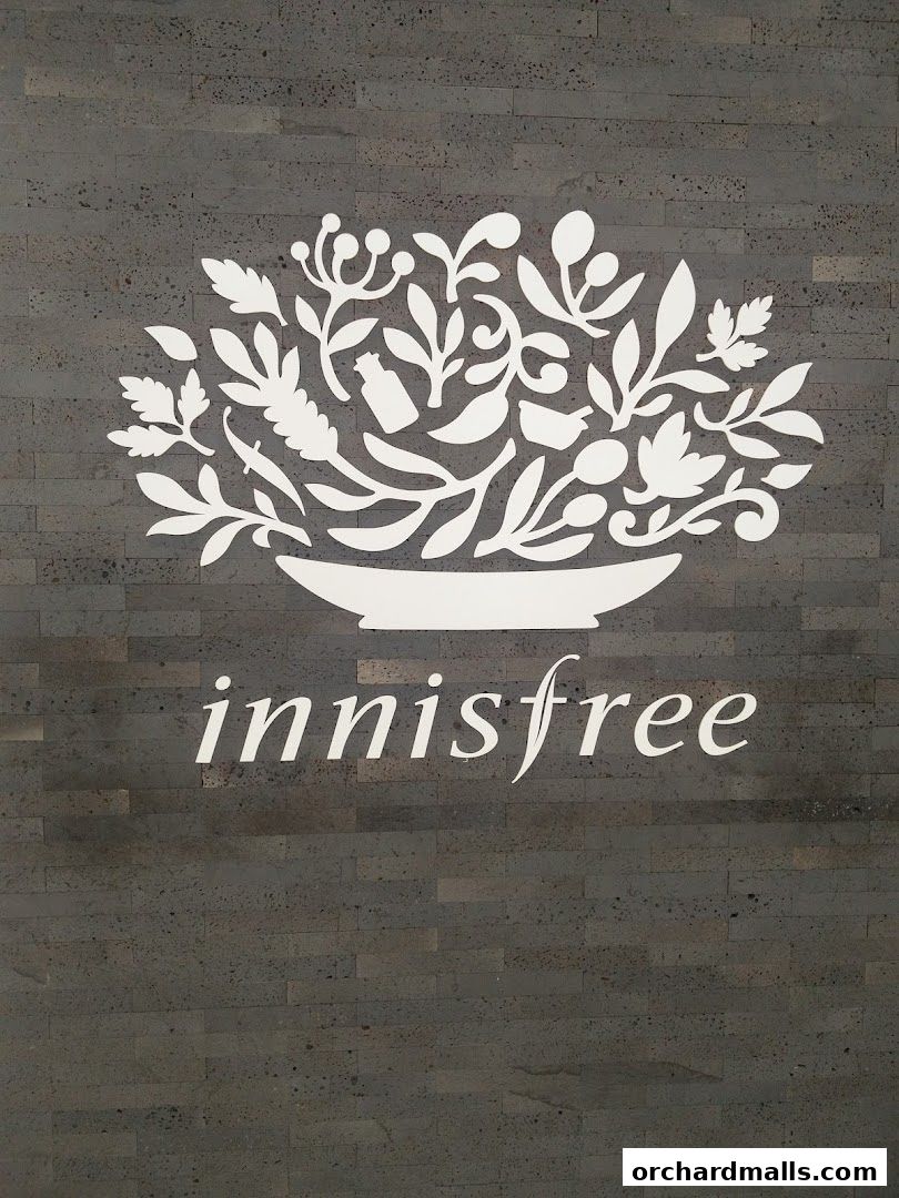Innisfree logo with floral design on a dark stone wall.