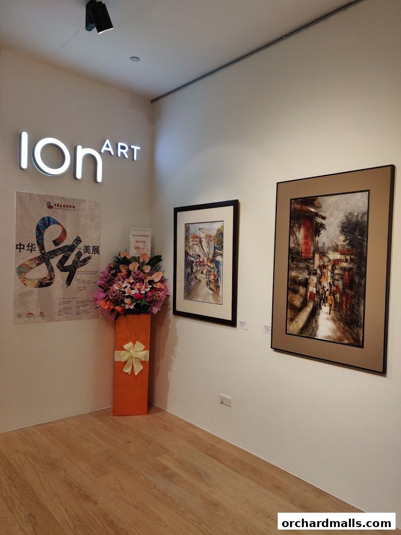 ION Art Gallery interior with paintings, floral arrangement, and signage.
