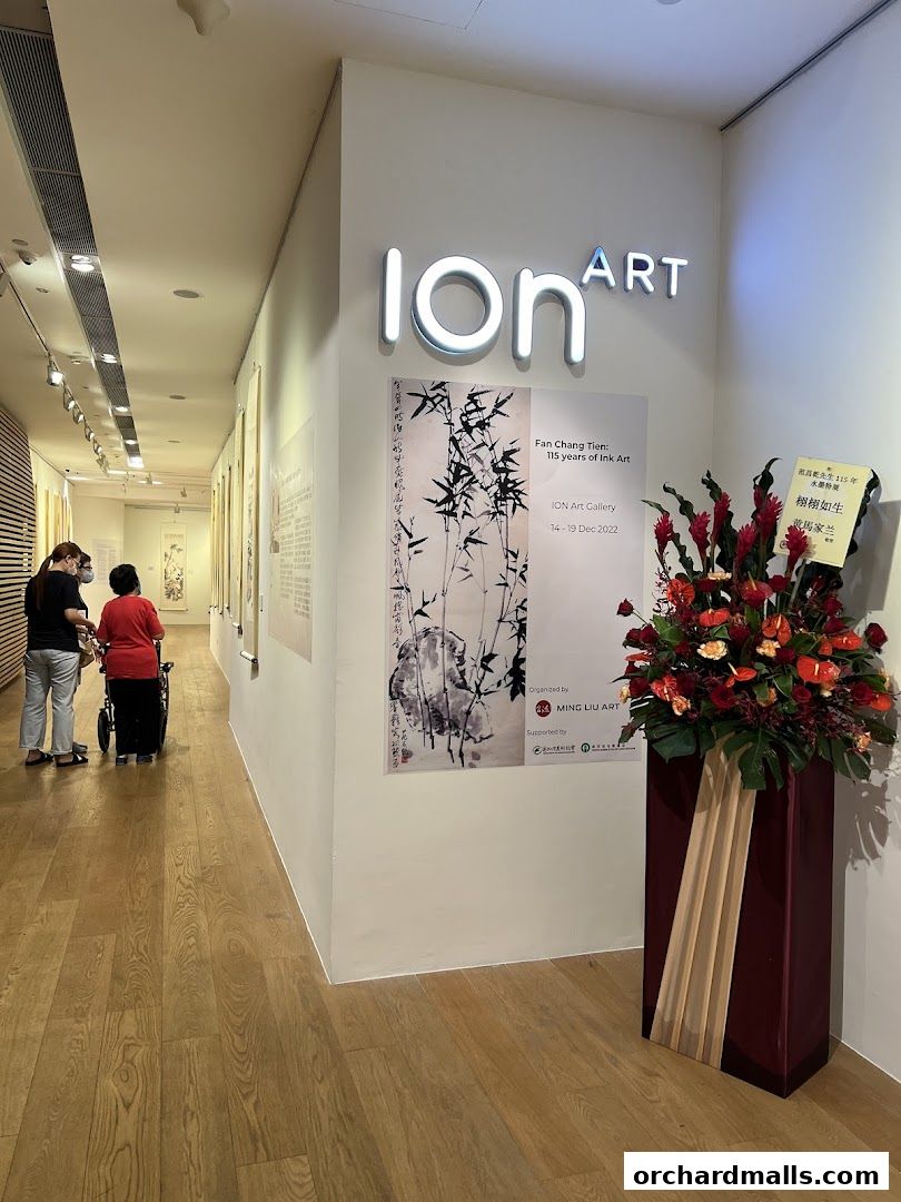 An art gallery hallway with an exhibition poster and floral arrangement.