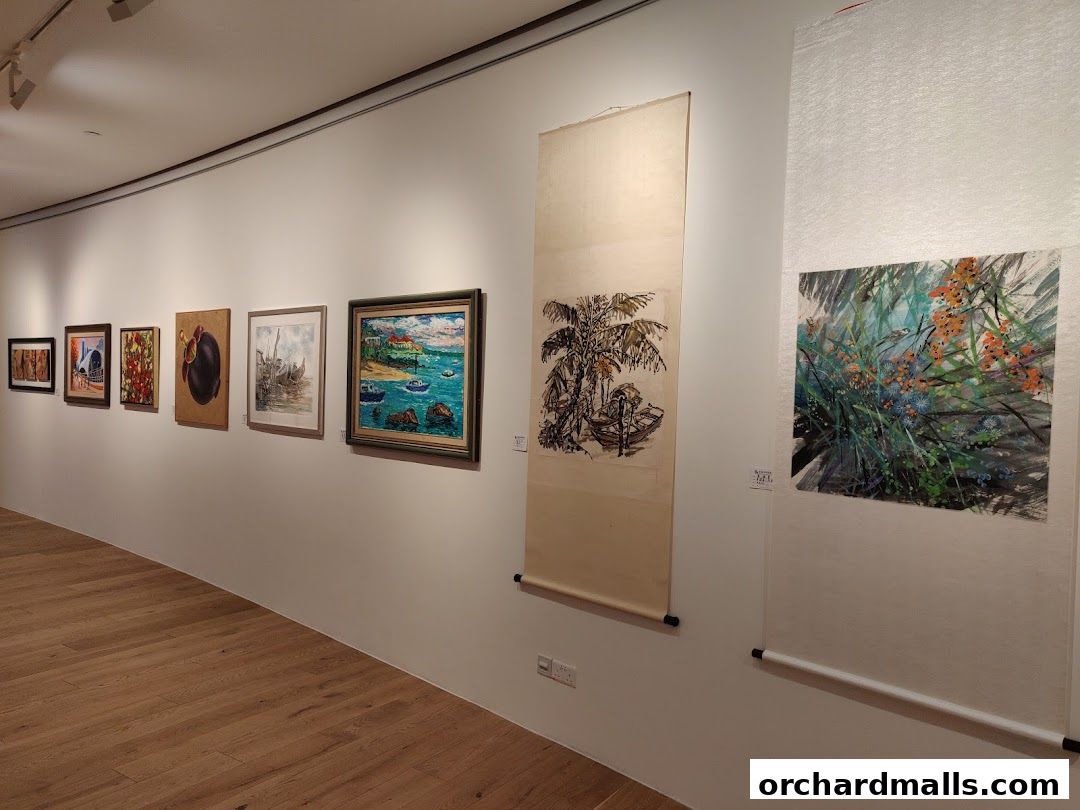 An art gallery interior with various paintings and scrolls displayed on a white wall.