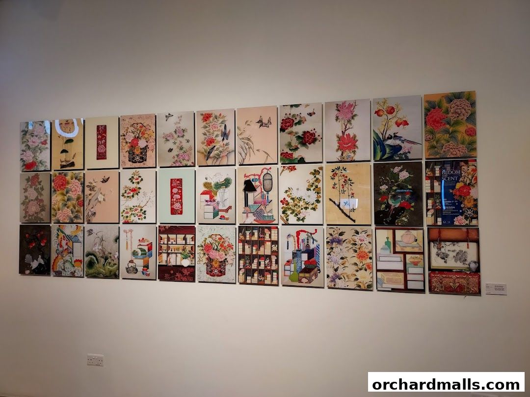 A wall displaying numerous artworks featuring floral and bird motifs in a traditional style.