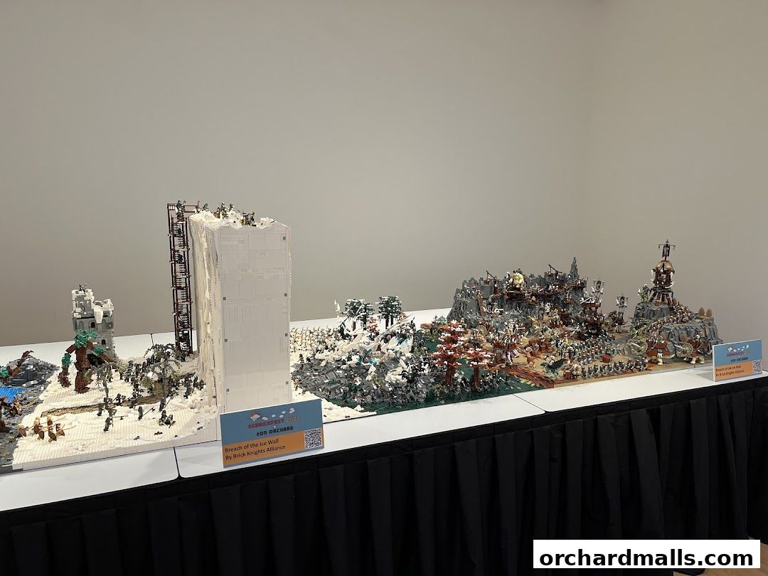 Intricate LEGO dioramas depicting epic battles and structures are displayed on tables.