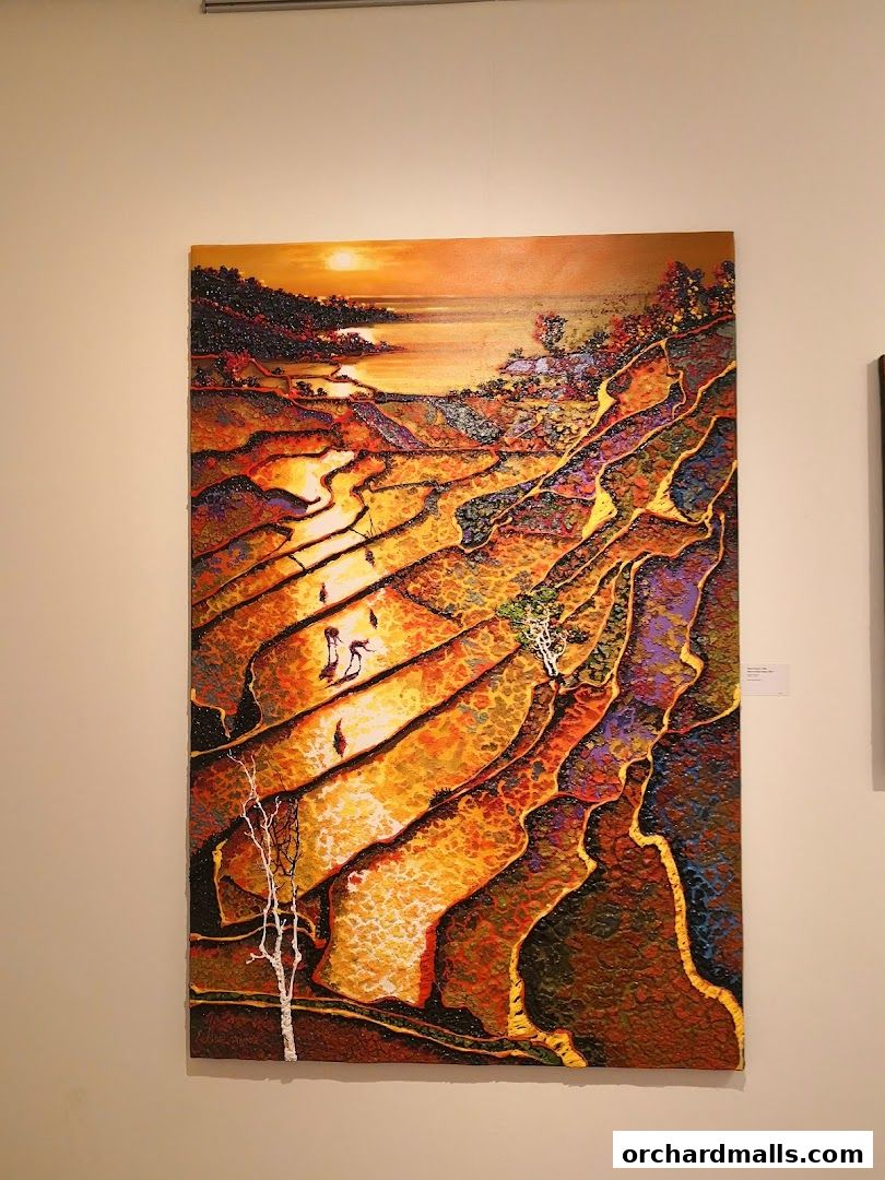 A vibrant textured painting of terraced fields at sunset, displayed on a white wall.