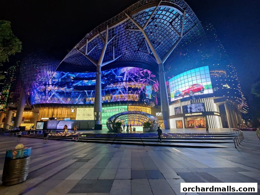 ION Sky building at night with vibrant digital displays and luxury brand storefronts.