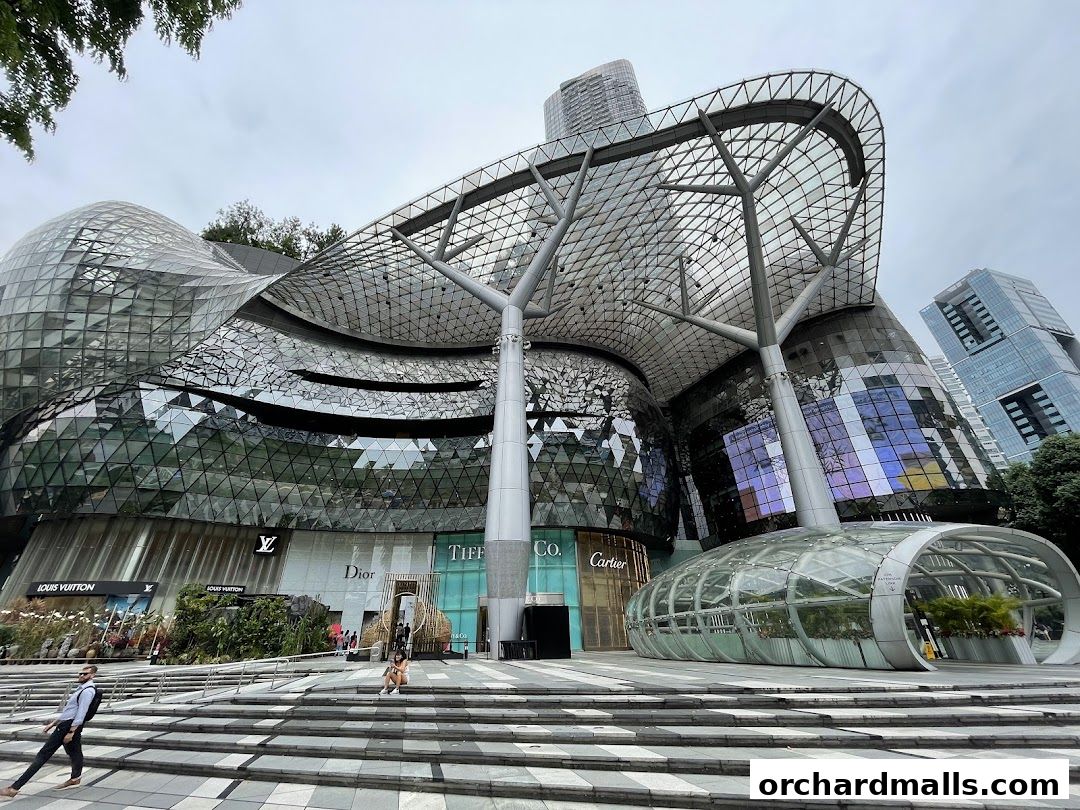Exterior view of a modern shopping mall with glass domes and prominent brand signage.