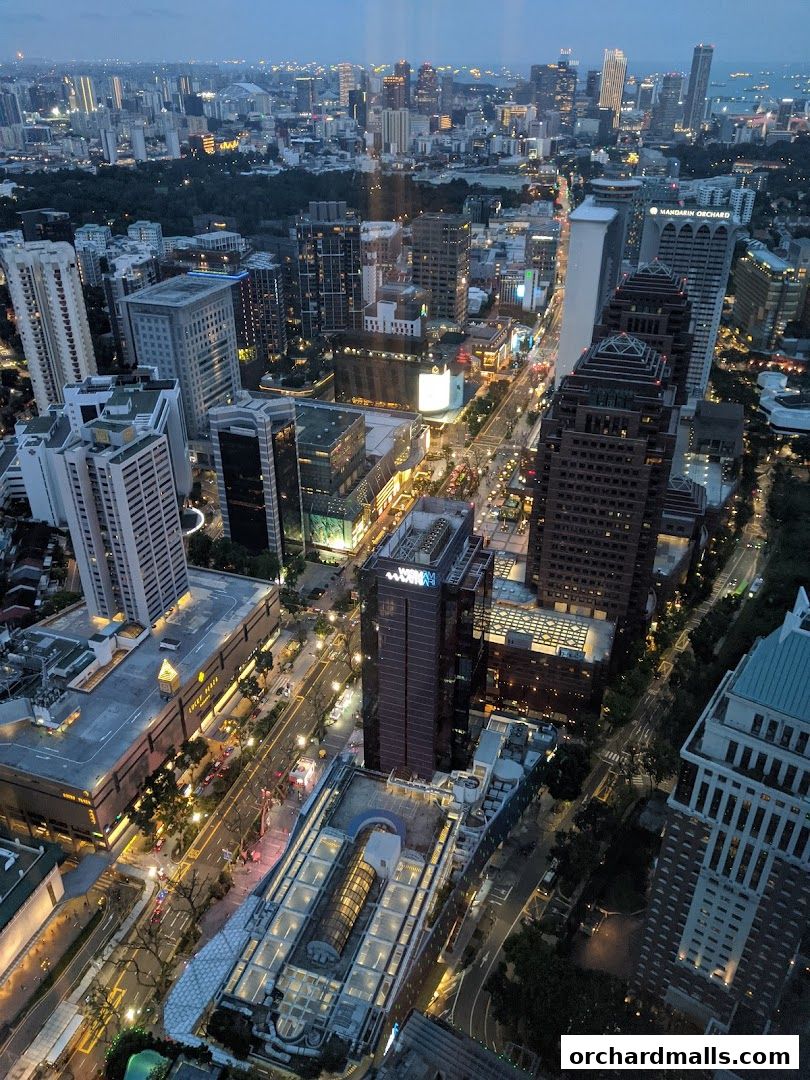 Aerial view of a city skyline at dusk, showcasing illuminated buildings and streets.