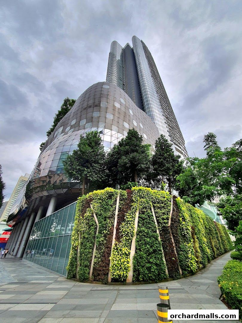 A striking modern building with a curved facade and a lush vertical garden.