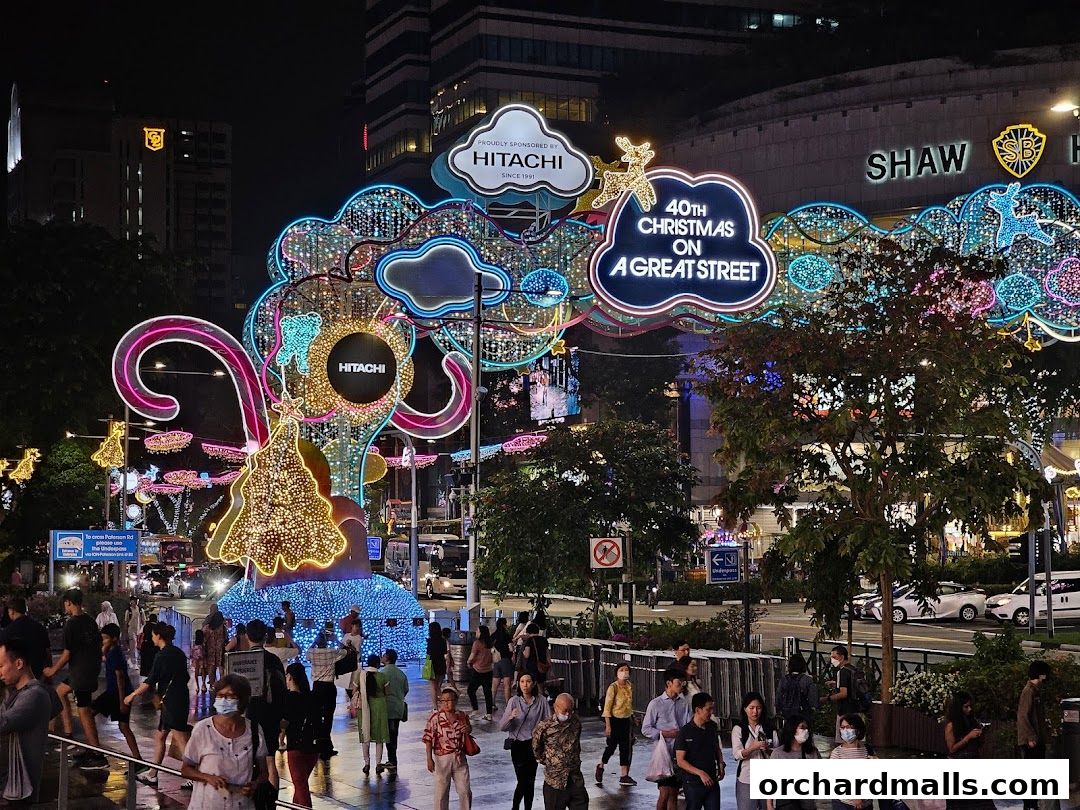 A festive street scene at night with elaborate Christmas lights and decorations.