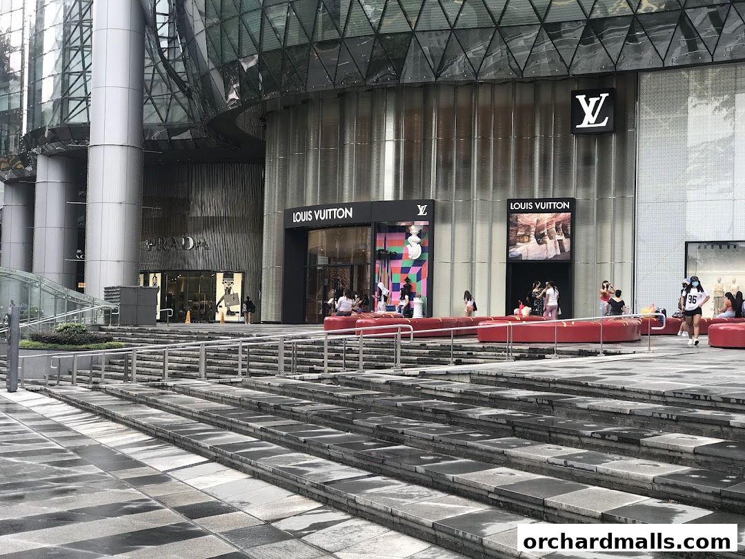 Exterior view of Louis Vuitton and Prada stores with people outside.