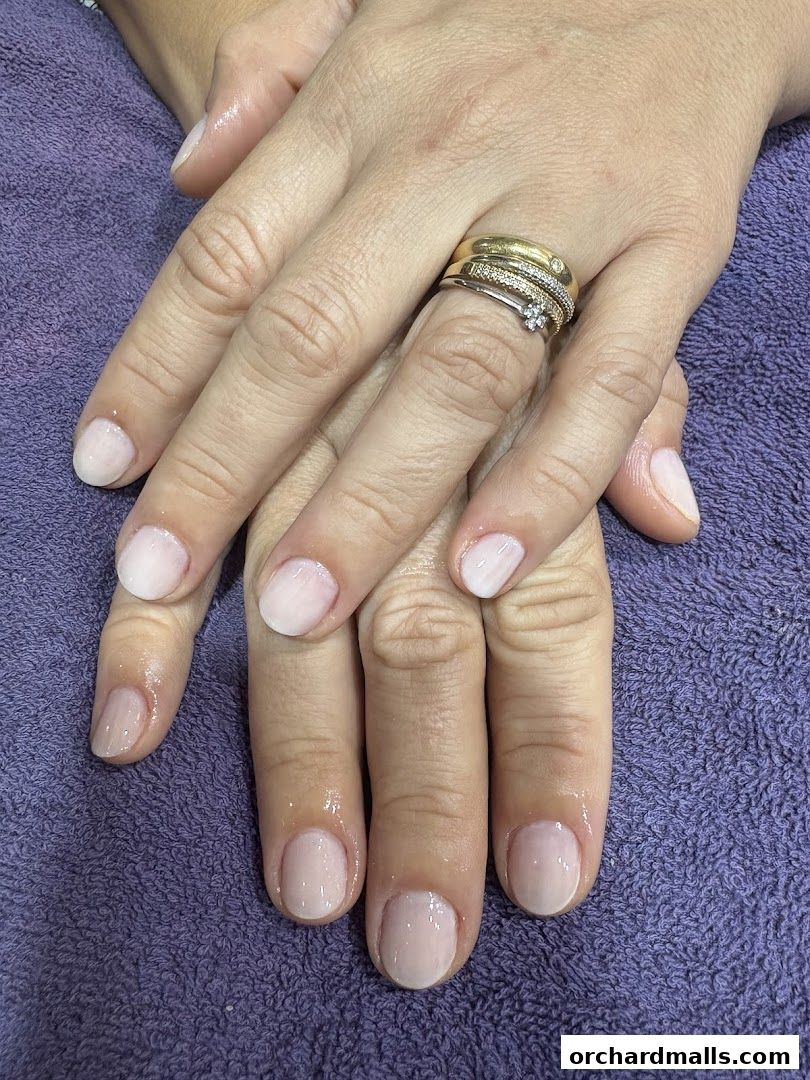 Close-up of hands with a fresh, natural-looking manicure and rings.